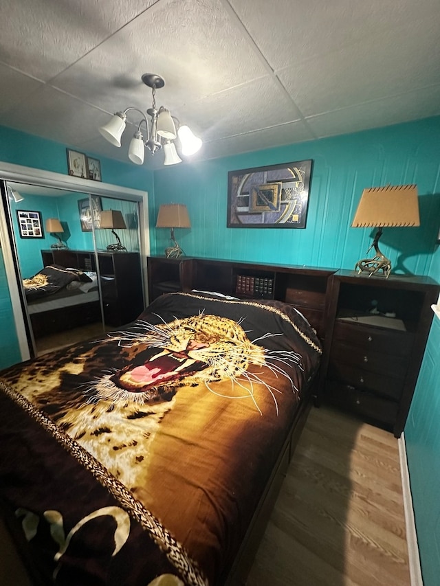 bedroom with wood-type flooring and ceiling fan with notable chandelier