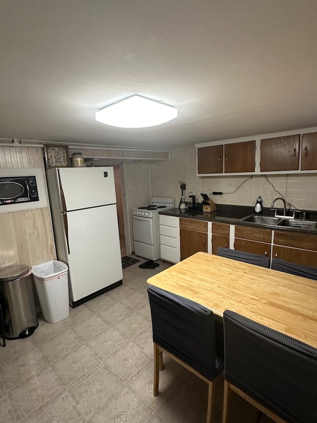 kitchen with dark brown cabinets, white appliances, and sink