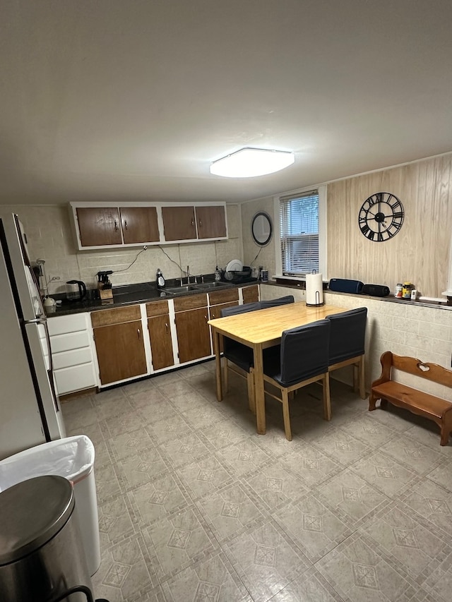 kitchen with white fridge, sink, and wooden walls