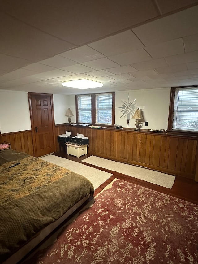 bedroom featuring carpet, a paneled ceiling, and wood walls