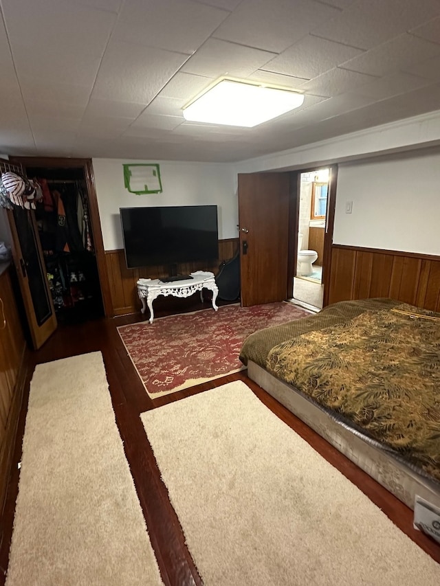 bedroom featuring dark hardwood / wood-style flooring and wooden walls