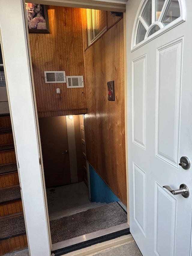 stairway featuring wooden walls