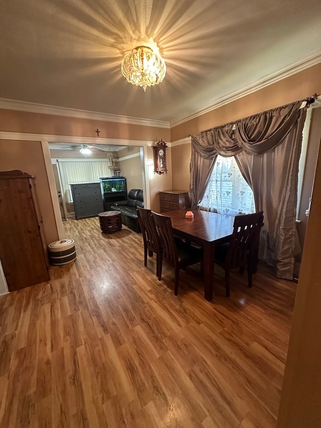 dining room with hardwood / wood-style floors, crown molding, and a notable chandelier