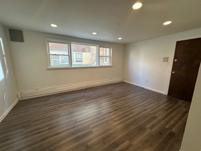 unfurnished room featuring a baseboard radiator and dark hardwood / wood-style flooring