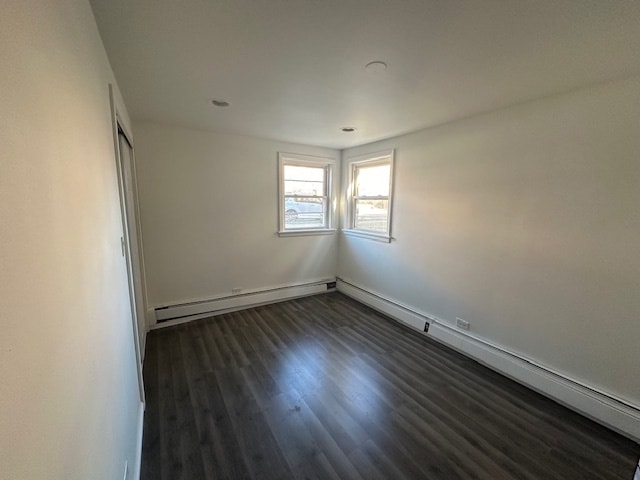 spare room featuring dark wood-type flooring and a baseboard heating unit