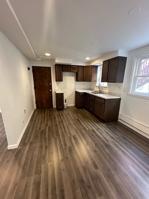 kitchen with dark wood-type flooring, dark brown cabinets, and sink