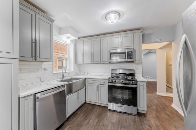 kitchen featuring dark hardwood / wood-style flooring, tasteful backsplash, stainless steel appliances, sink, and gray cabinets