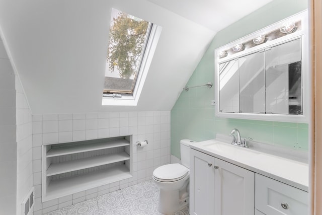 bathroom featuring vaulted ceiling with skylight, vanity, tile walls, tile patterned flooring, and toilet