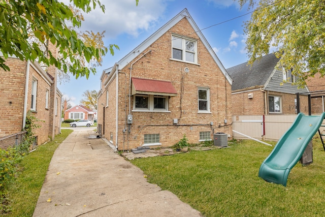 rear view of house featuring a lawn and central AC unit