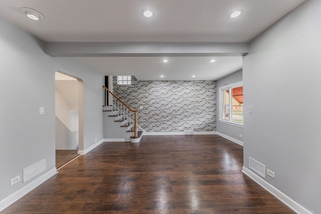 unfurnished living room featuring tile walls and dark wood-type flooring