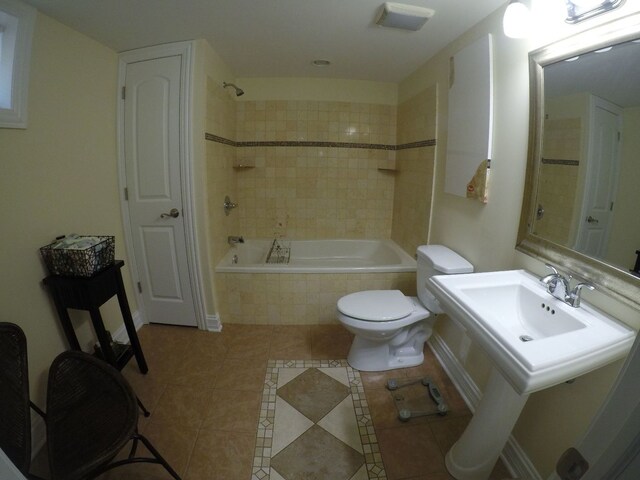 bathroom featuring toilet, tile patterned flooring, and tiled shower / bath