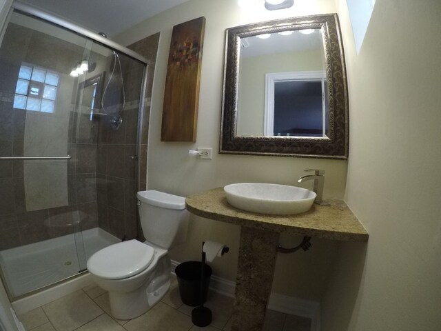 bathroom featuring tile patterned floors, toilet, a shower with shower door, and sink