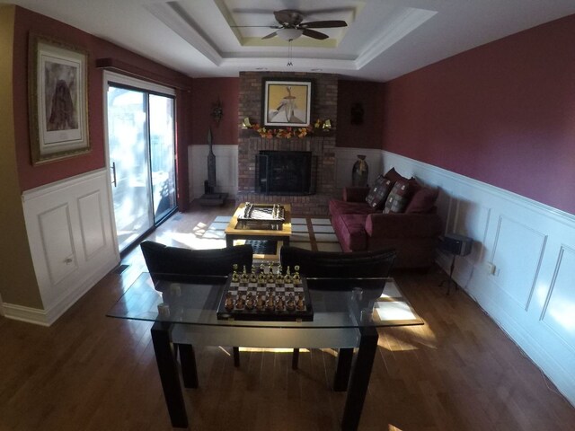 living room with a fireplace, wood-type flooring, a raised ceiling, and ceiling fan