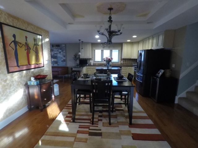 dining space with a chandelier, light hardwood / wood-style floors, and a raised ceiling