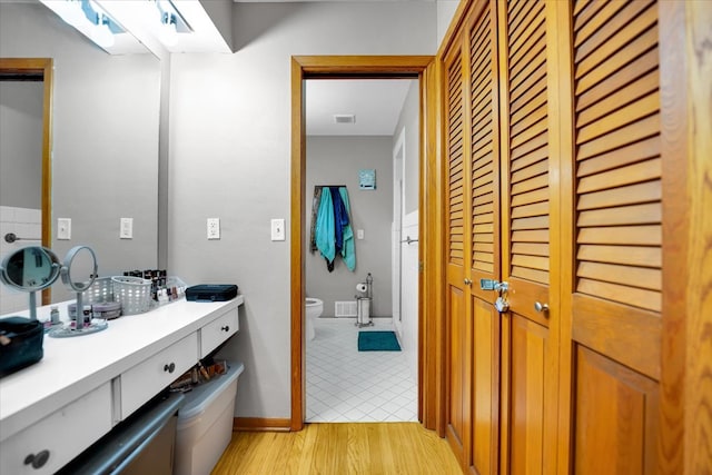 bathroom featuring toilet, vanity, and hardwood / wood-style floors