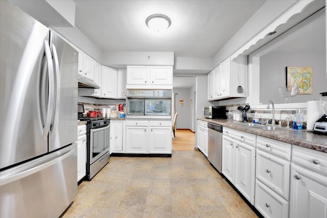 kitchen featuring white cabinetry, appliances with stainless steel finishes, sink, and light stone counters