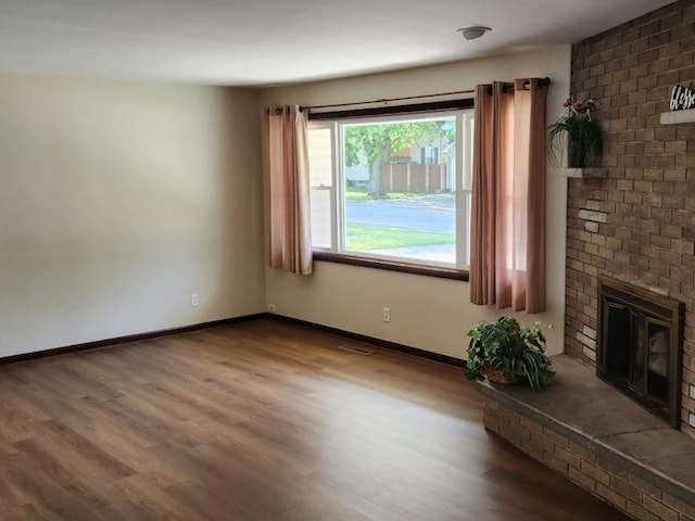 unfurnished living room featuring a brick fireplace and hardwood / wood-style floors