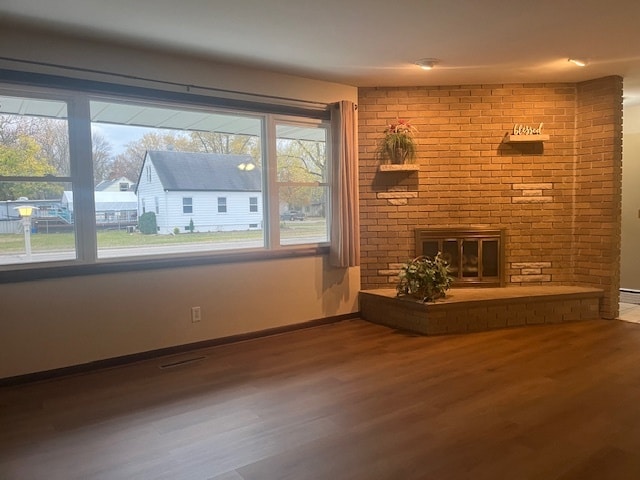 unfurnished living room with a brick fireplace and hardwood / wood-style floors