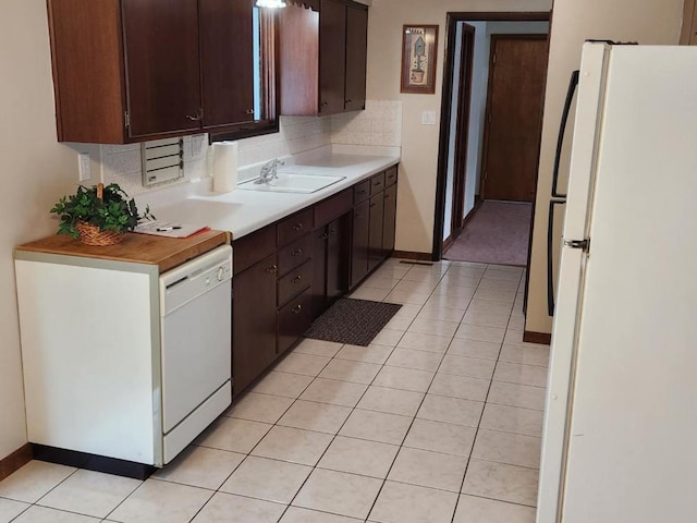 kitchen with decorative backsplash, dark brown cabinetry, sink, and white appliances