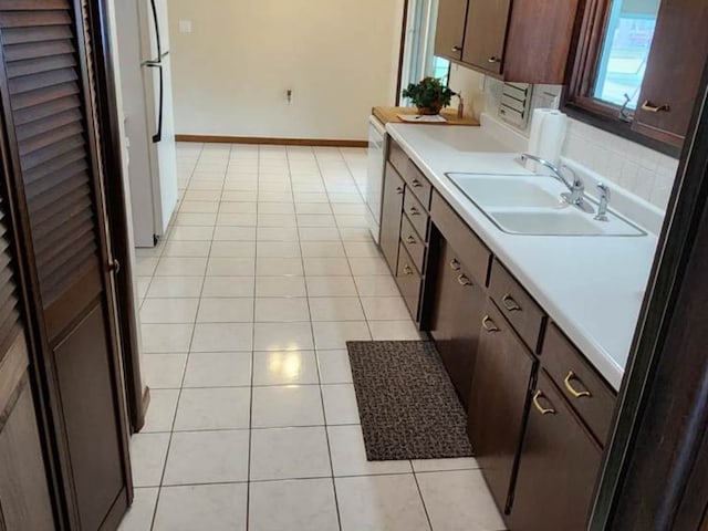 kitchen with dark brown cabinetry, light tile patterned flooring, sink, and white refrigerator