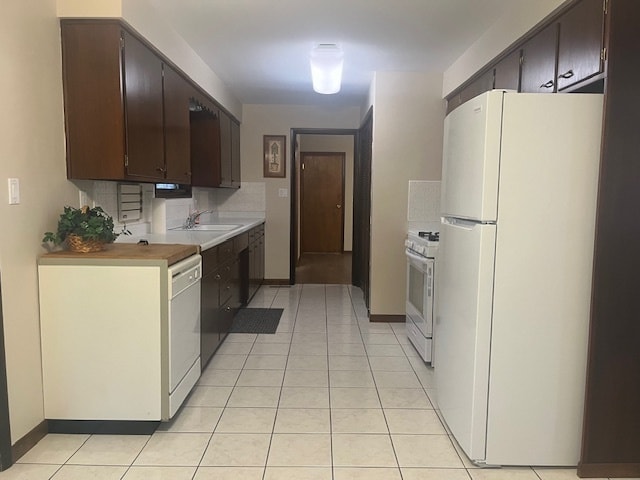 kitchen with light tile patterned floors, white appliances, dark brown cabinets, and sink