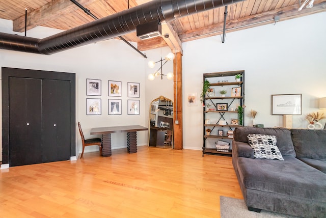 living room with beam ceiling, hardwood / wood-style floors, a towering ceiling, a chandelier, and wood ceiling