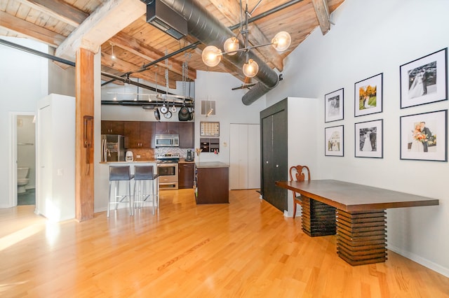 kitchen with stainless steel appliances, wood ceiling, high vaulted ceiling, a kitchen breakfast bar, and beam ceiling