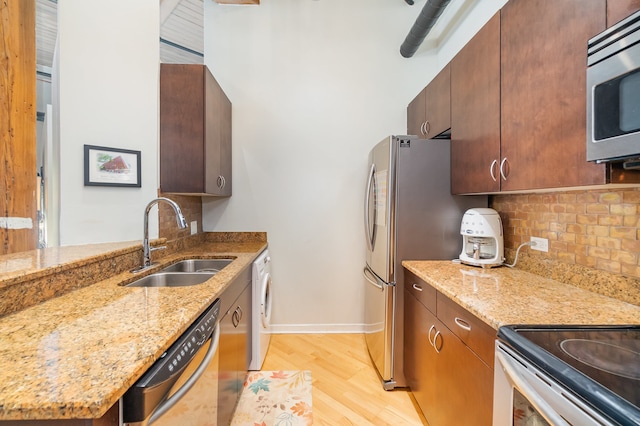 kitchen featuring appliances with stainless steel finishes, sink, light stone counters, and light hardwood / wood-style flooring