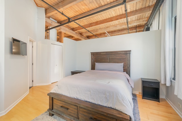 bedroom with light hardwood / wood-style floors, beamed ceiling, and wooden ceiling