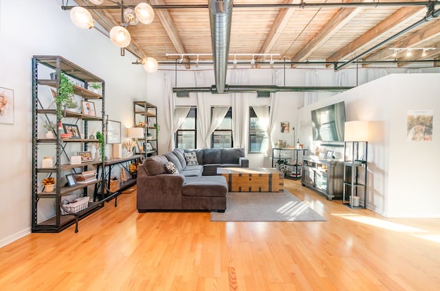 living room with a high ceiling, hardwood / wood-style floors, wooden ceiling, and beam ceiling