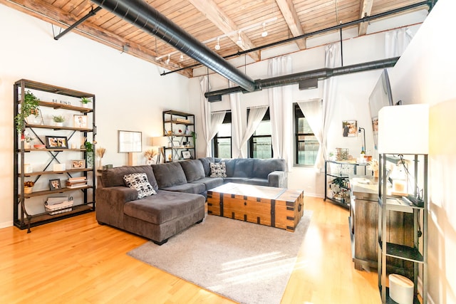 living room with beamed ceiling, wood ceiling, a towering ceiling, and light wood-type flooring