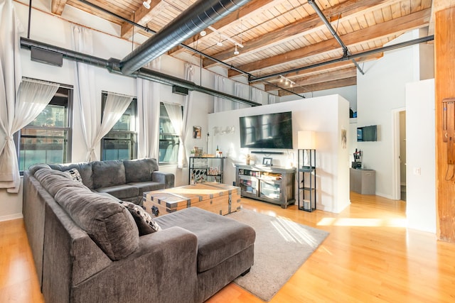 living room featuring a towering ceiling, light hardwood / wood-style flooring, beamed ceiling, and wood ceiling