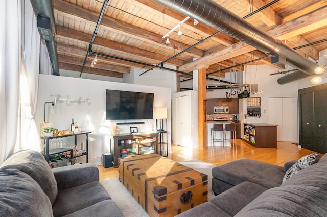 living room with beam ceiling, wood ceiling, a towering ceiling, and light hardwood / wood-style flooring