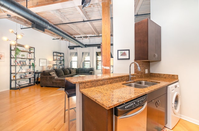 kitchen with light wood-type flooring, stainless steel dishwasher, sink, and washer / dryer