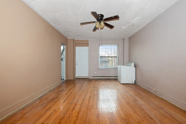 spare room with ceiling fan, light wood-type flooring, baseboard heating, a textured ceiling, and washer / clothes dryer