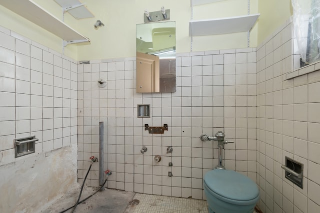 bathroom with toilet, tile patterned floors, and tile walls