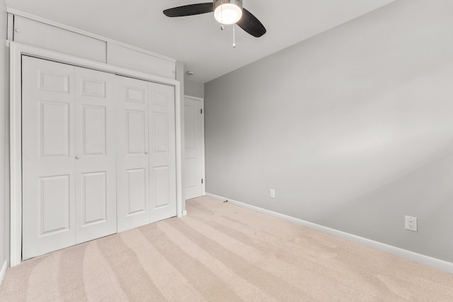 unfurnished bedroom with light carpet, a closet, and ceiling fan