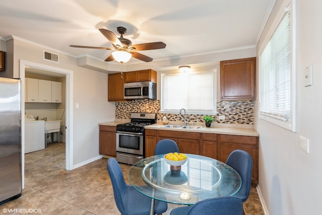 kitchen with a wealth of natural light, sink, decorative backsplash, and appliances with stainless steel finishes