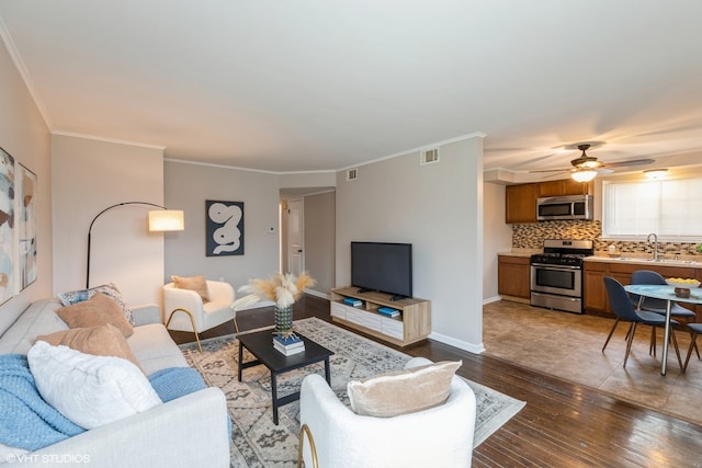 living room with ornamental molding, ceiling fan, sink, and dark hardwood / wood-style floors