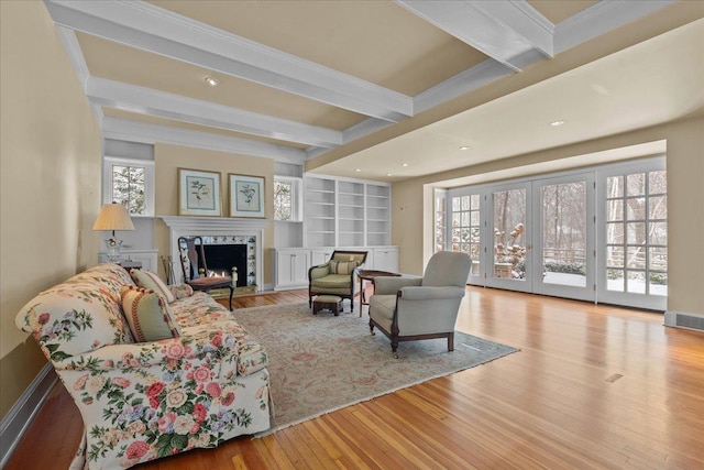 living room featuring crown molding, beamed ceiling, and light hardwood / wood-style flooring