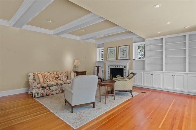 living room featuring built in features, light hardwood / wood-style floors, and beam ceiling