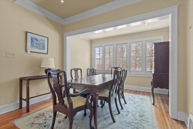 dining room with ornamental molding and light hardwood / wood-style floors