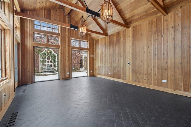 unfurnished room with wooden walls, high vaulted ceiling, an inviting chandelier, wooden ceiling, and beamed ceiling