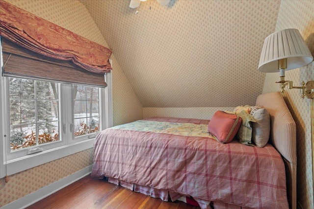 bedroom featuring ceiling fan, hardwood / wood-style floors, and vaulted ceiling