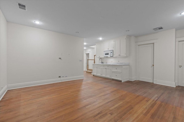 unfurnished living room with sink and light hardwood / wood-style flooring