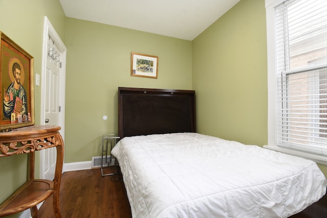 bedroom featuring dark hardwood / wood-style floors, vaulted ceiling, and multiple windows