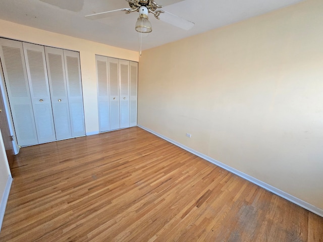 unfurnished bedroom with multiple closets, light hardwood / wood-style flooring, and ceiling fan