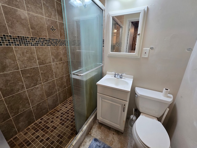 bathroom with a shower with door, vanity, and toilet