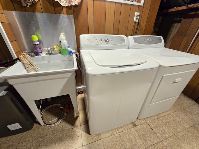 clothes washing area featuring separate washer and dryer and wooden walls