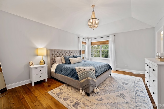 bedroom with dark hardwood / wood-style flooring, lofted ceiling, and an inviting chandelier